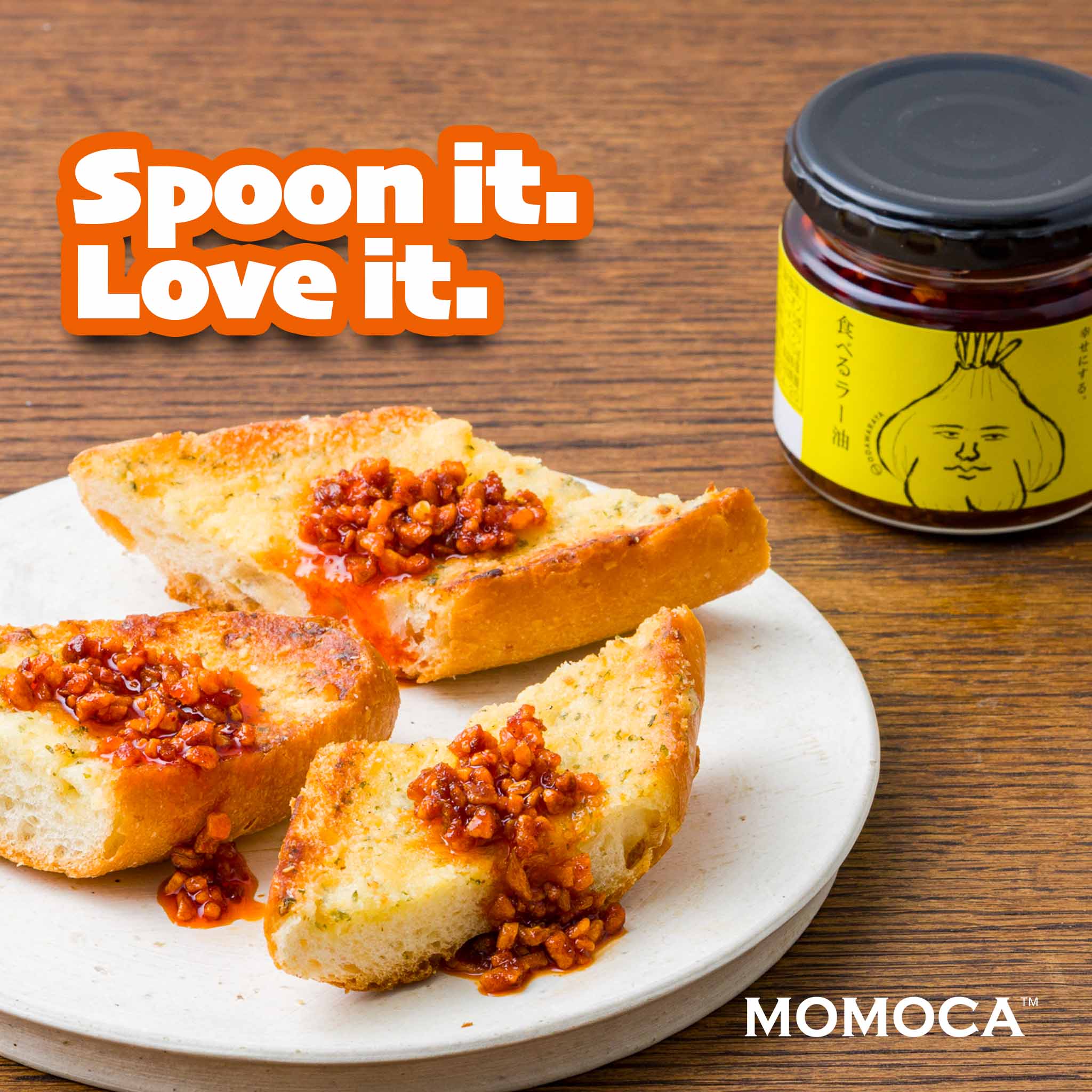 Bread slices with a red spread on a white plate, jar of red spread with yellow label on wooden surface, 'Spoon it. Love it.