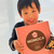 A young boy excitedly holding up a box of authentic Japanese snacks with the word Monica on it.
