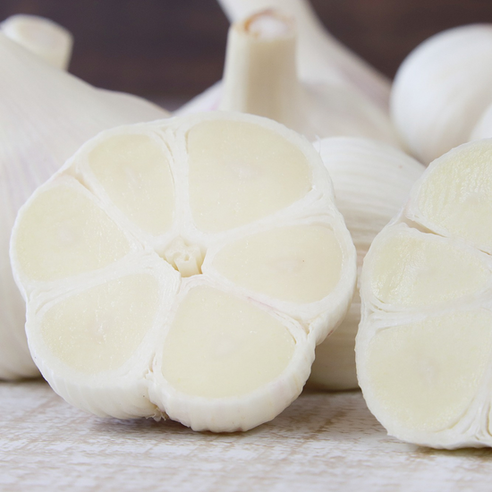 A group of white garlic cloves on a wooden surface, perfect for authentic Japanese snacks.