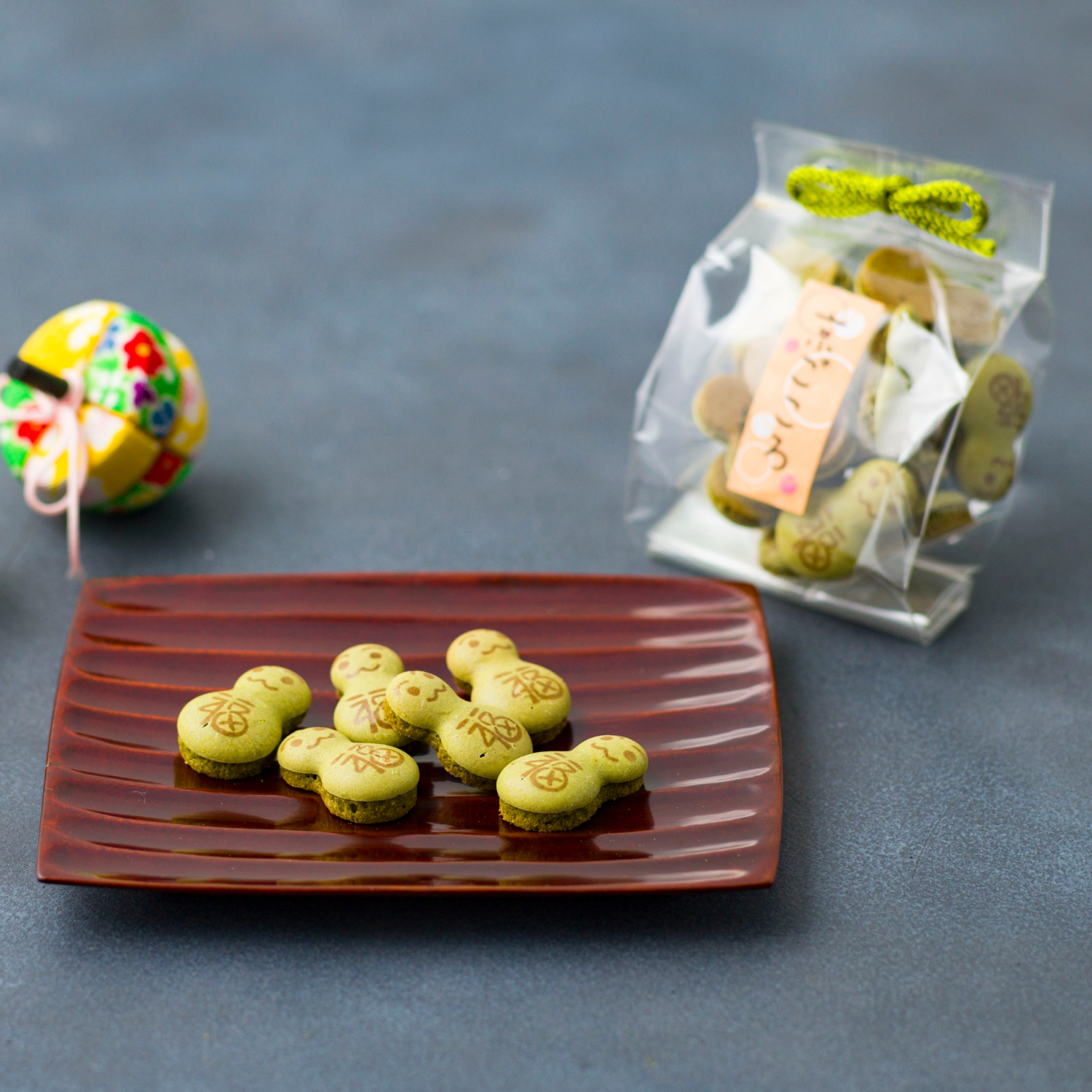 Green cookies on a brown plate with a bag of cookies in the background